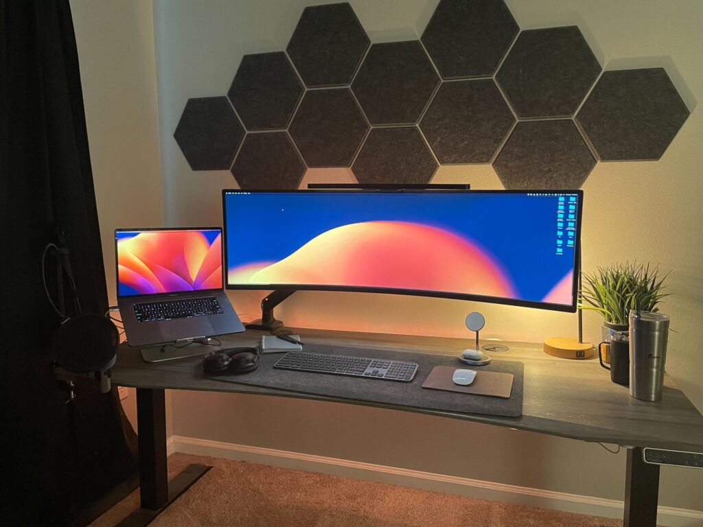 A crisp and tidy home office in Florida with a very wide monitor and beautiful lighting behind the monitor and around the desk.