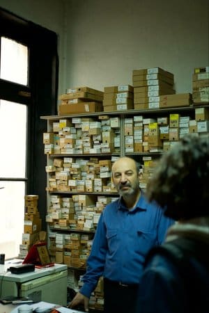 Businessman in front of shelves of inventory, speaking with a customer