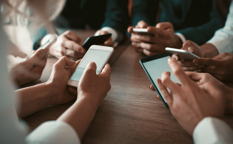 Close up of the hands and mobile phones of a group of co-workers