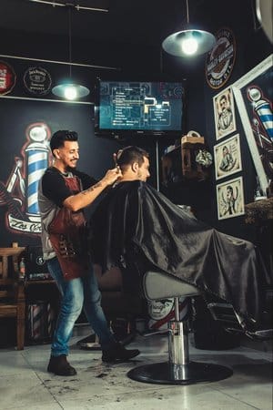 Owner in a modern, urban barbershop providing a hair cut to a client