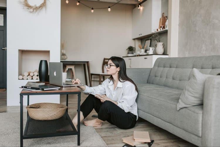 Woman comfortably sitting on living room floor while using her computer