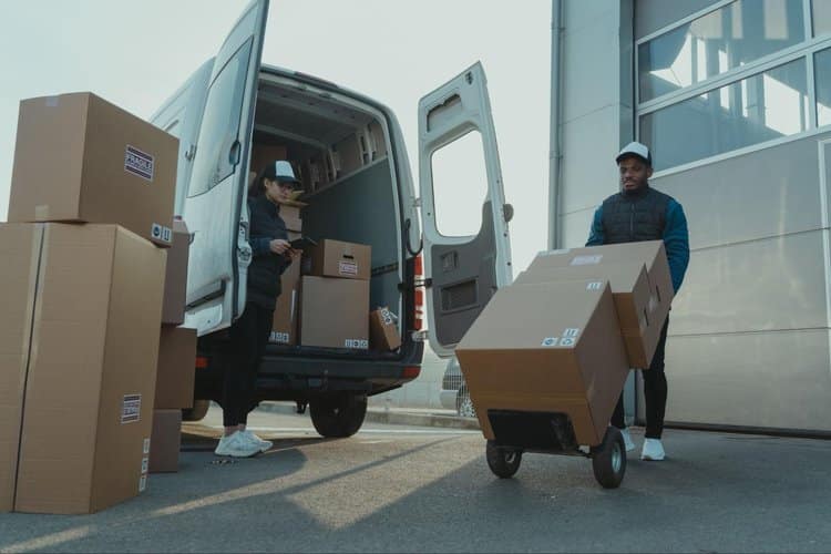 Two delivery drivers unloading boxes from the back of a delivery van