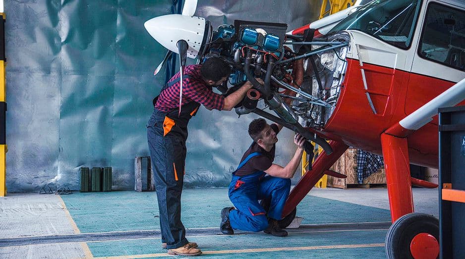 Photograph of mechanics working on a small airplane.
