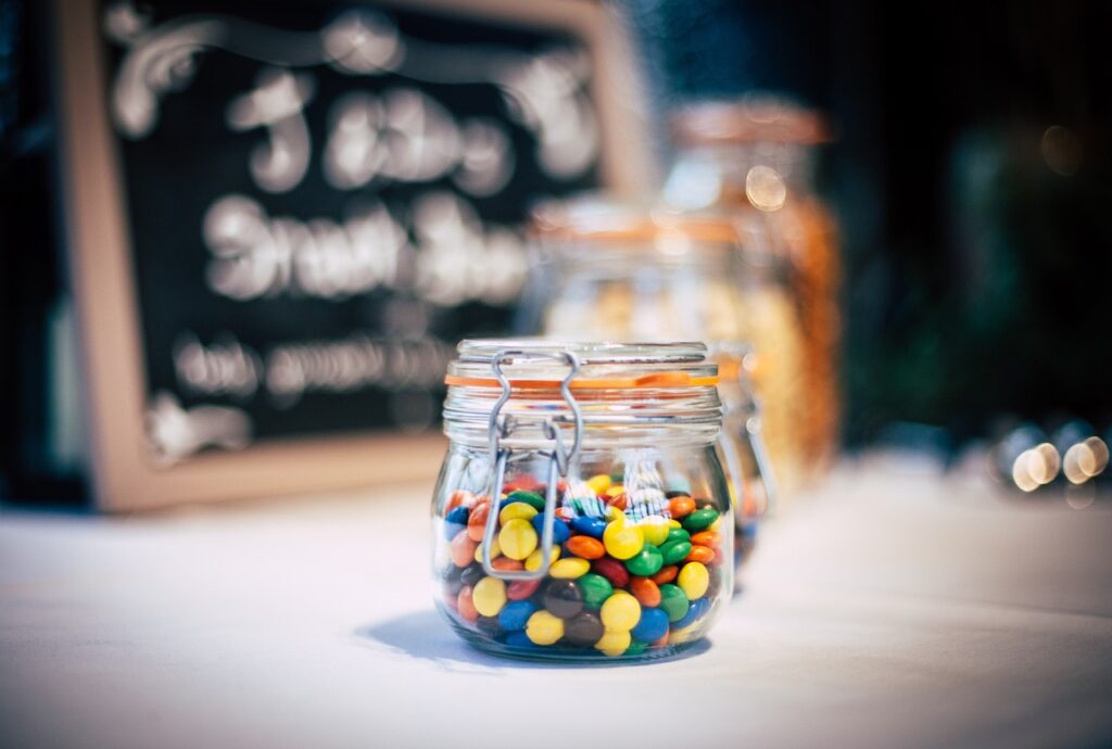 Photo of mason jars full of candy, with the front jar being full of M&Ms.