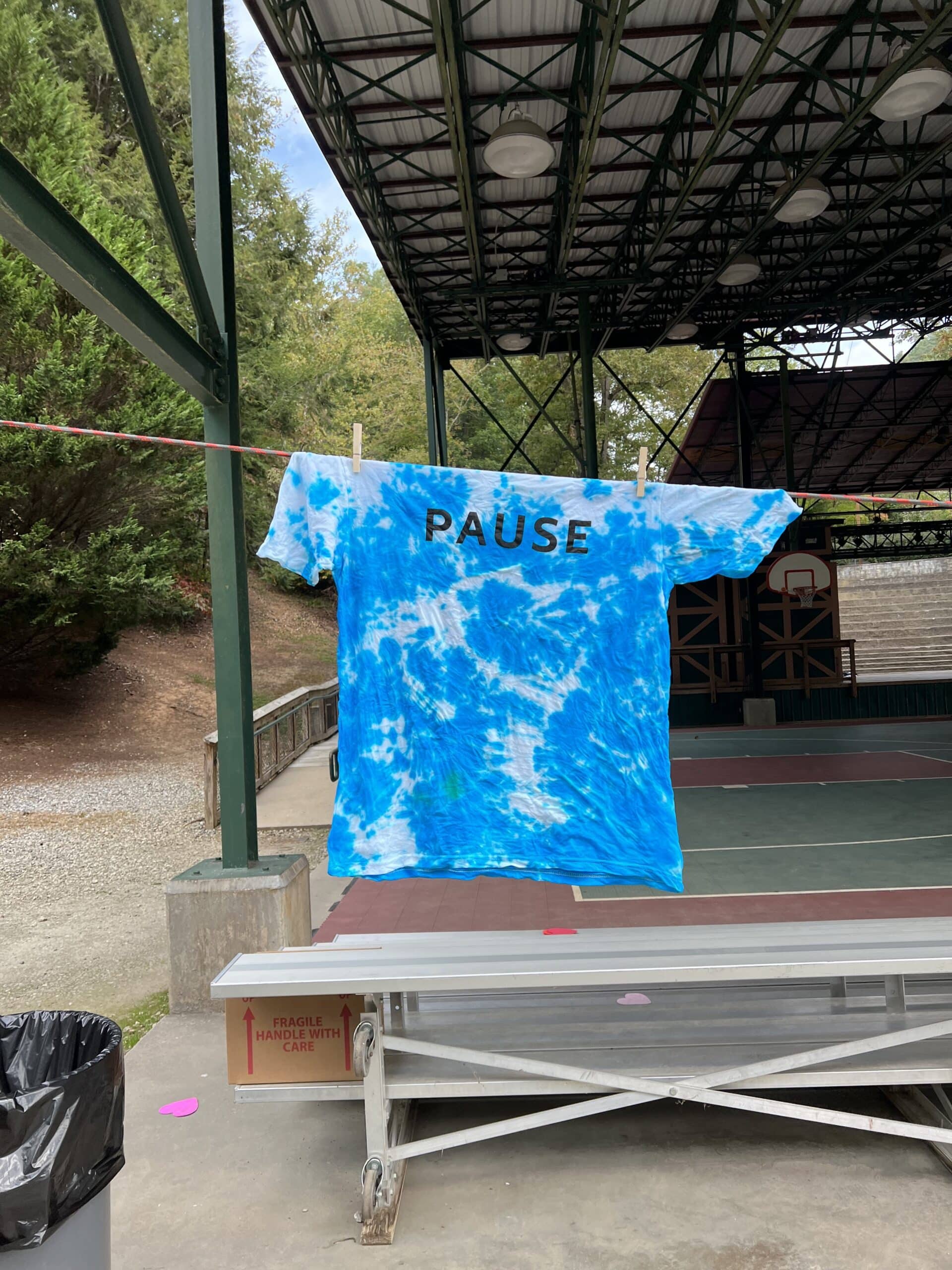 Photo of a blue tie-dyed t-shirt, with the Pause logo.