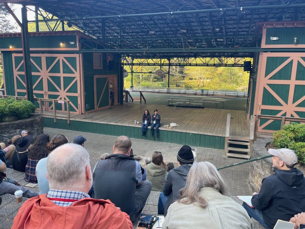 Photo of the stage at Pause 2023, from the audience, with two speakers seated onstage.