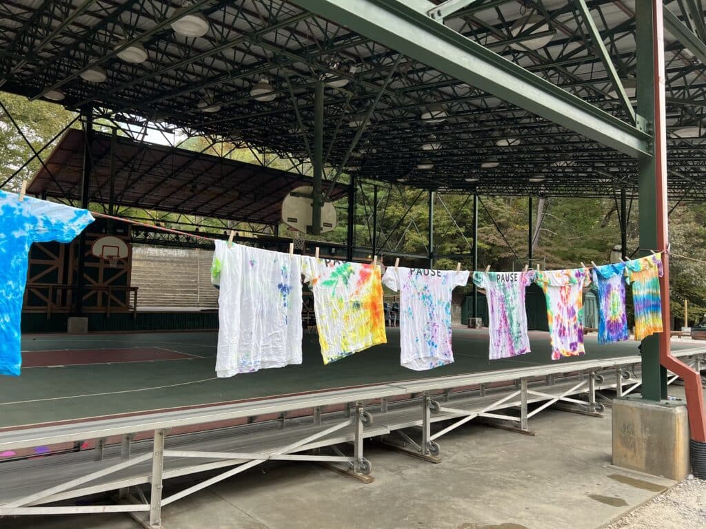 Photo of several tie-dye t-shirts drying on a clothesline.