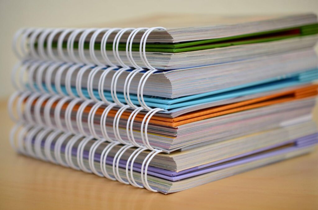 Photo of a stack of four thick, colorful ring-bound notebooks