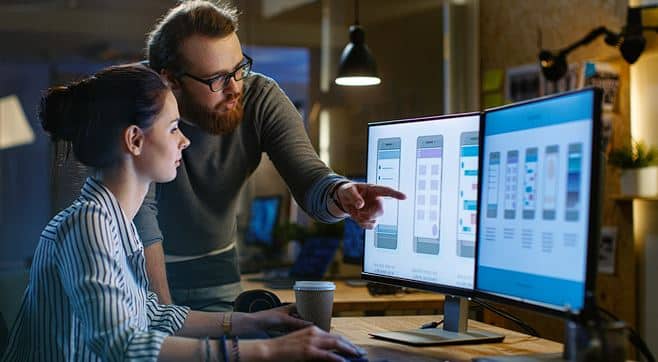 Photograph of a man and woman working together on a mobile app development project, guided by the principles of quality management systems.