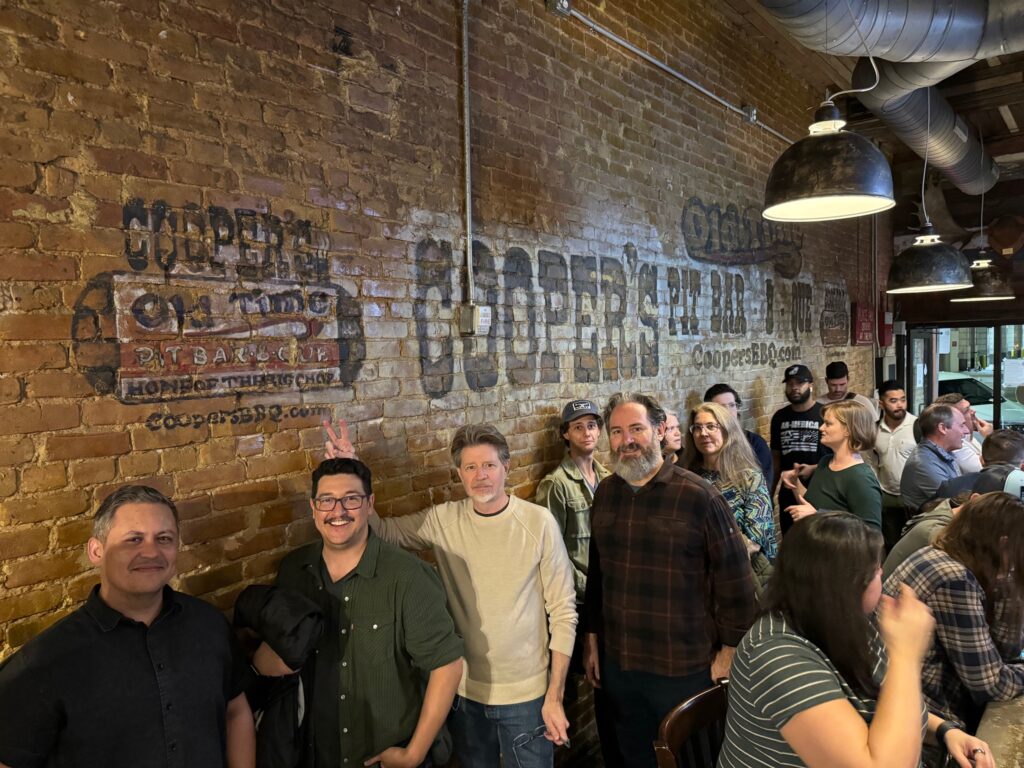 The Portage Bay team waiting in line at Cooper's BBQ in Austin, Texas, with Dan making rabbit ears behind Jacob's head.