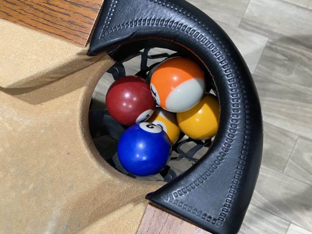 Overhead photo of five pool balls in the corner pocket of a pool table.