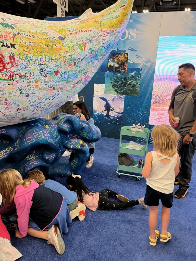 Photo of children adding words and drawings to a large art display at SXSW.