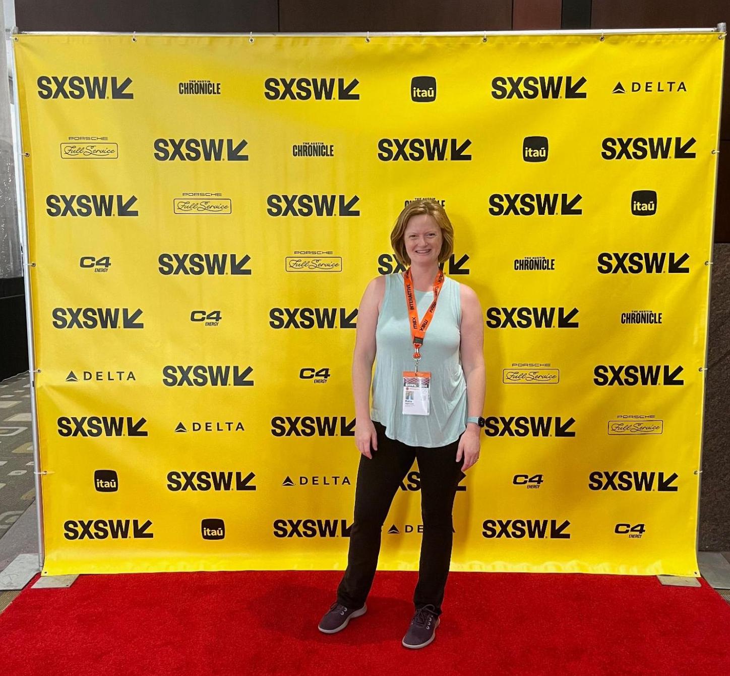 Photo of Kate standing in front of the photo op banner at South by Southwest in Austin, Texas.
