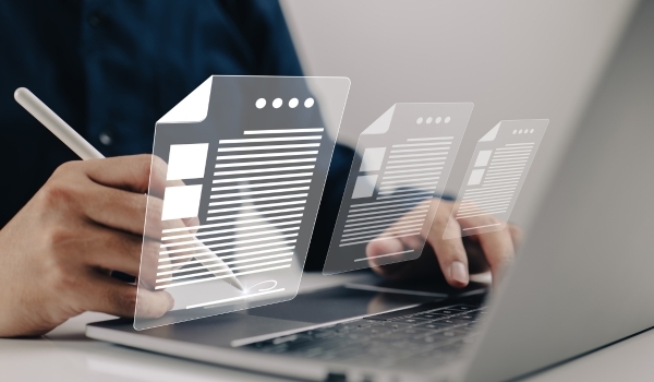 A person's hands typing and drawing on a laptop touch pad with an Apple Pencil. The documents they're working on are hovering outside the laptop screen and above their hands like holograms. This article talks about the benefits of using separate development and production environments.